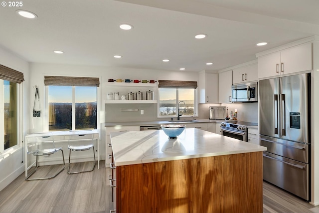 kitchen with sink, stainless steel appliances, a center island, and white cabinets