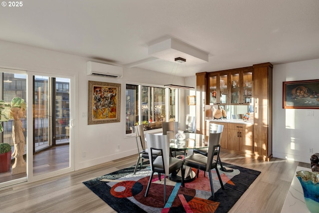 dining room with light hardwood / wood-style flooring and a wall unit AC