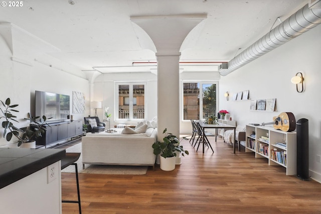 living area featuring wood finished floors and ornate columns