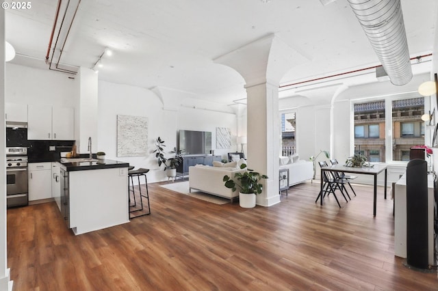kitchen with a peninsula, a kitchen breakfast bar, gas stove, open floor plan, and dark countertops