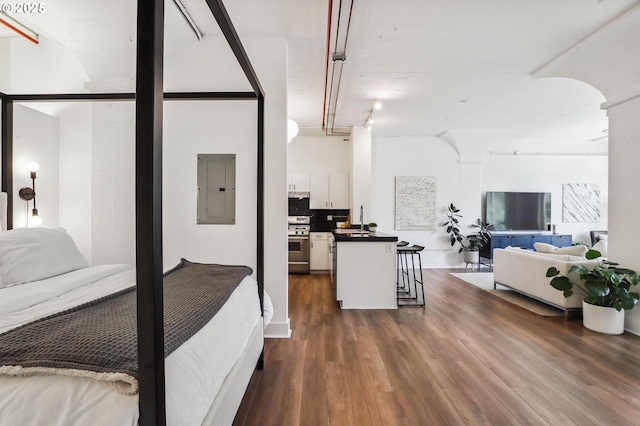 bedroom featuring electric panel, dark wood-type flooring, and a sink