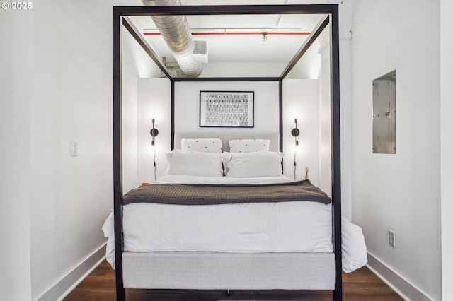 bedroom featuring electric panel, baseboards, and wood finished floors
