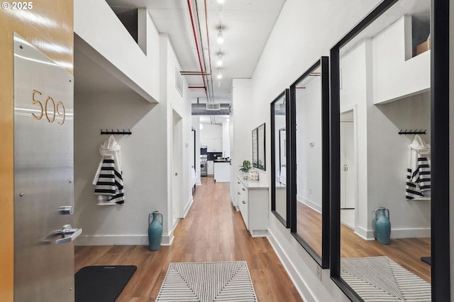 hallway featuring light wood-style flooring, baseboards, and visible vents