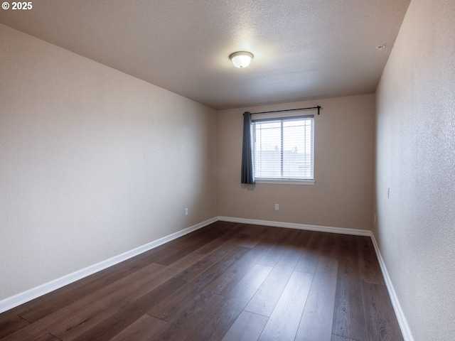 empty room with dark hardwood / wood-style floors and a textured ceiling