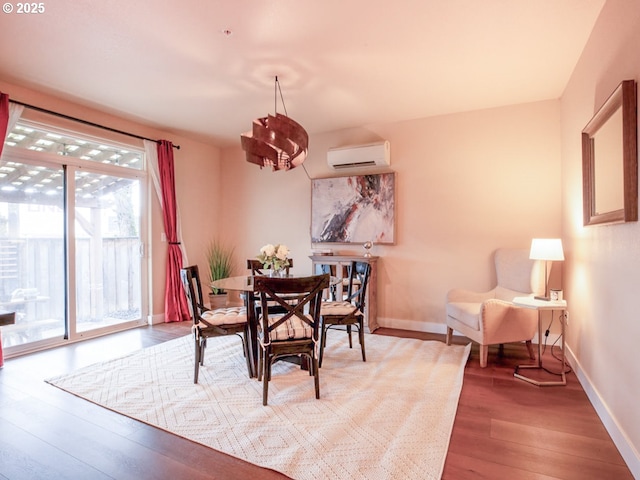 dining space featuring an inviting chandelier, a wall mounted air conditioner, and wood-type flooring