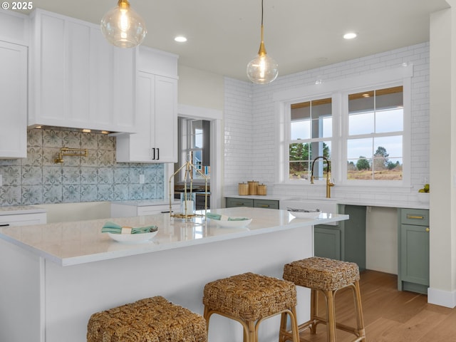 kitchen featuring light wood-type flooring, white cabinetry, pendant lighting, and decorative backsplash