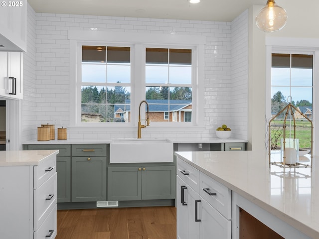 kitchen featuring visible vents, wood finished floors, a sink, pendant lighting, and a wealth of natural light