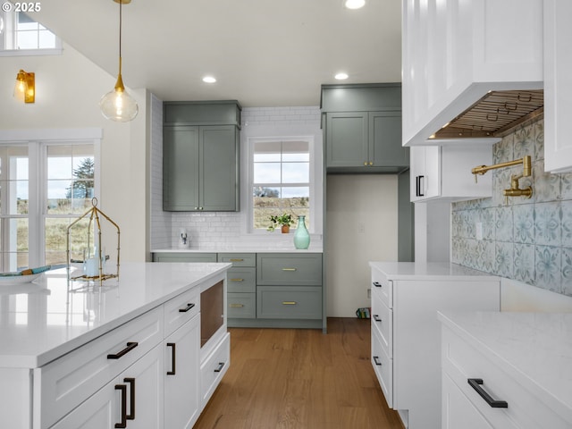 kitchen featuring a wealth of natural light, premium range hood, hanging light fixtures, and decorative backsplash