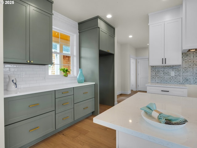 kitchen featuring light stone countertops, light wood-style flooring, and decorative backsplash