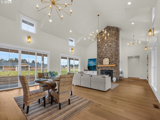 dining area with a chandelier, visible vents, a fireplace, and light wood finished floors