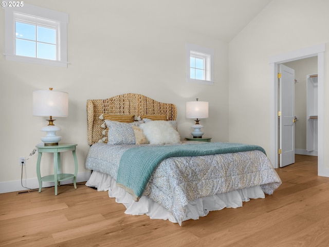 bedroom featuring lofted ceiling, baseboards, and wood finished floors