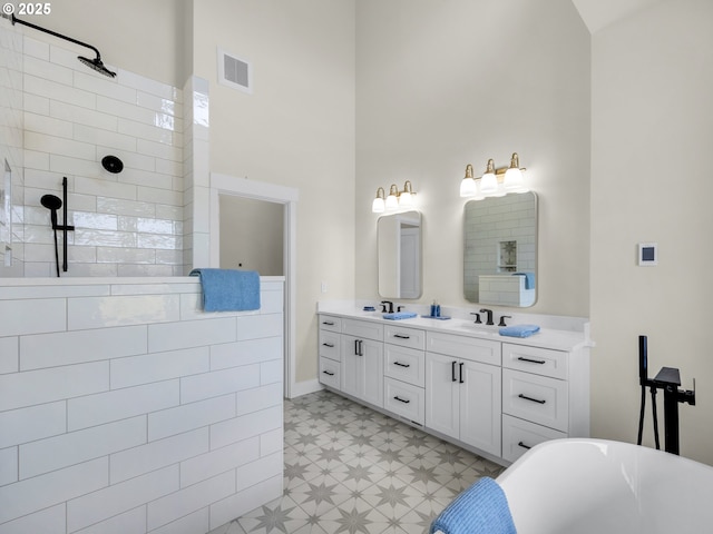 full bathroom featuring a sink, visible vents, a freestanding bath, tile patterned floors, and double vanity