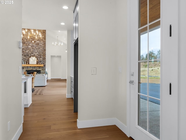 hall featuring light wood-type flooring, baseboards, a notable chandelier, and recessed lighting