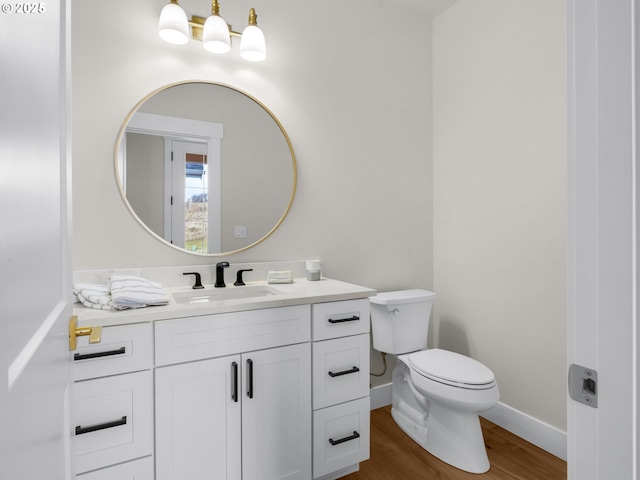 half bath featuring toilet, baseboards, wood finished floors, and vanity