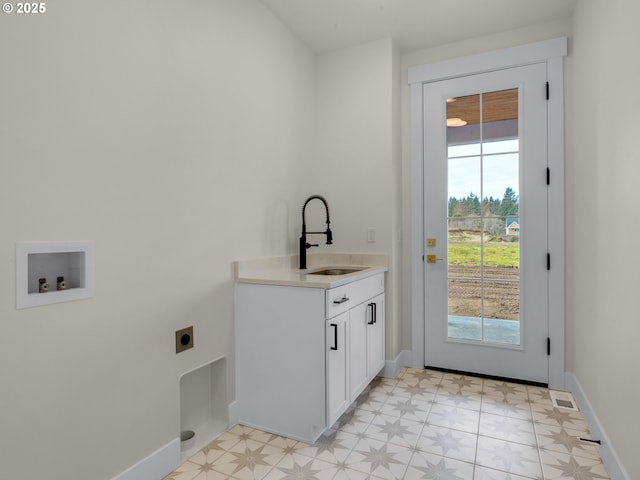 clothes washing area featuring cabinet space, a sink, electric dryer hookup, and a healthy amount of sunlight