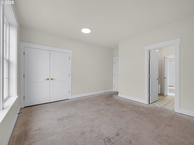 unfurnished bedroom with multiple windows, concrete floors, and baseboards