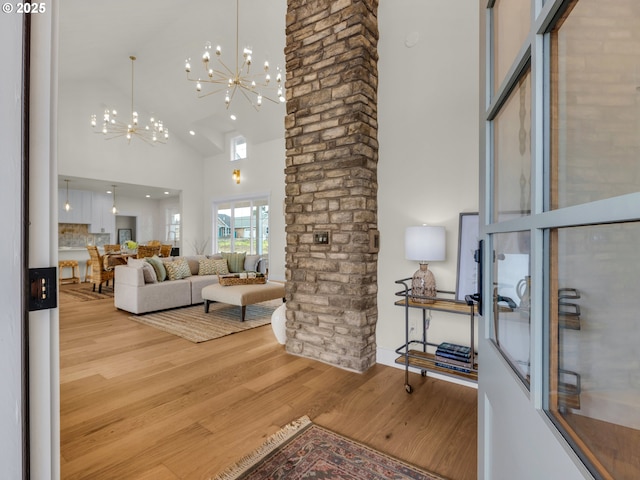 living room featuring light wood-style floors, high vaulted ceiling, and an inviting chandelier