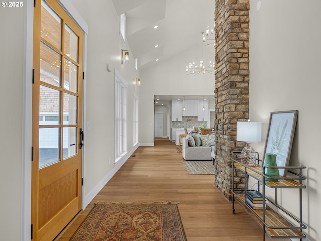 foyer with baseboards, a chandelier, light wood-style flooring, high vaulted ceiling, and recessed lighting