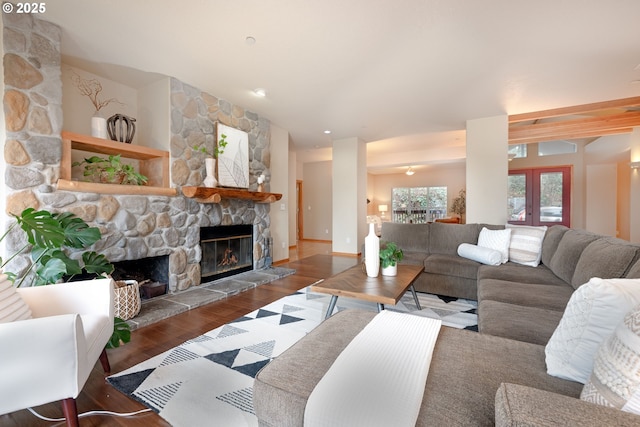 living room with dark wood-type flooring, a stone fireplace, and french doors