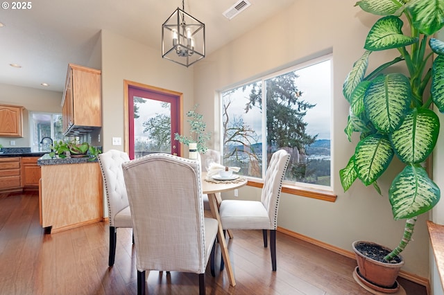 dining area with a notable chandelier, dark hardwood / wood-style floors, and a healthy amount of sunlight