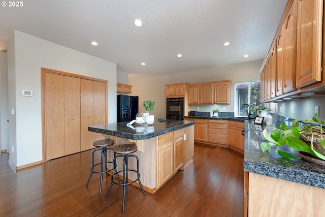 kitchen with a center island, sink, dark hardwood / wood-style flooring, and black appliances