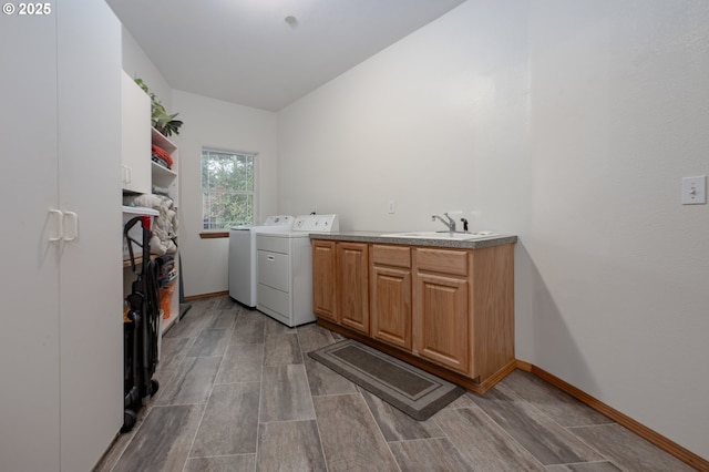 laundry area featuring cabinets, separate washer and dryer, and sink