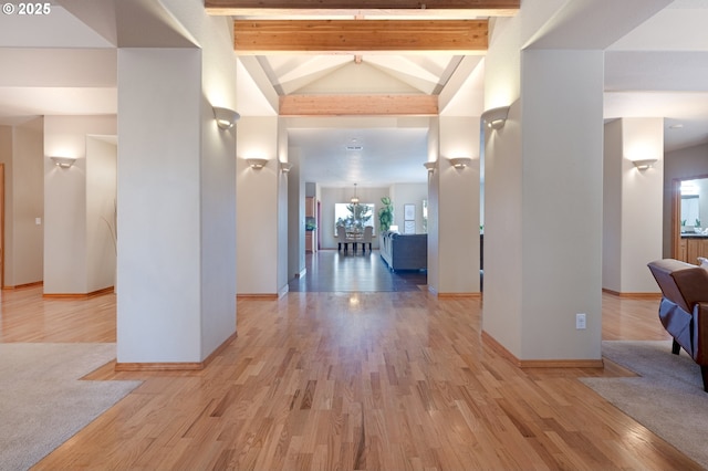 hallway with high vaulted ceiling, beam ceiling, and light hardwood / wood-style floors