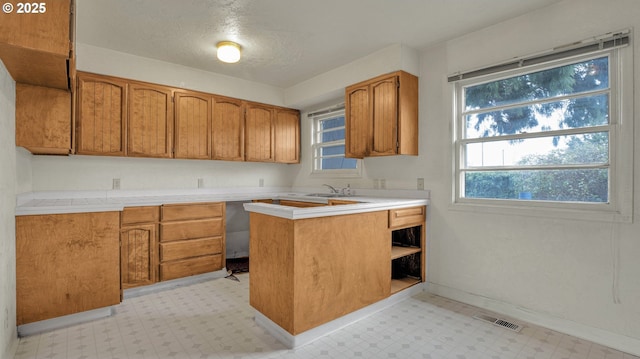 kitchen featuring sink, a textured ceiling, and kitchen peninsula