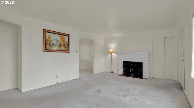 unfurnished living room featuring a brick fireplace and light carpet