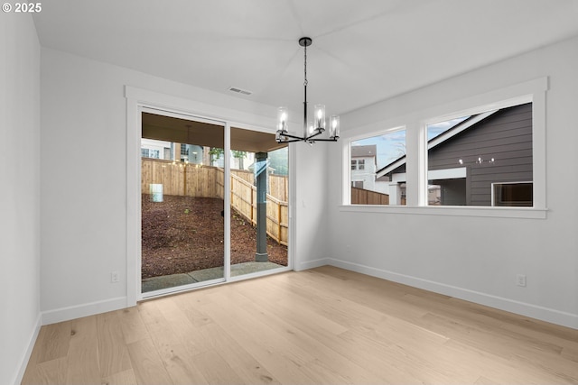 unfurnished dining area with hardwood / wood-style floors and a chandelier