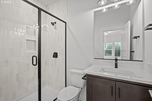 bathroom with a shower with door, vanity, and toilet