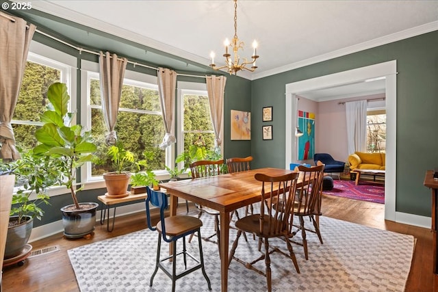 dining room featuring hardwood / wood-style flooring, ornamental molding, and a notable chandelier