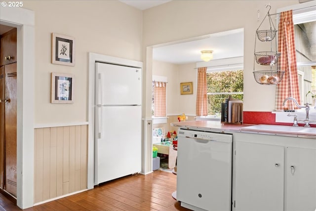 kitchen with white cabinetry, sink, white appliances, and light wood-type flooring