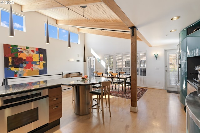 1240 NW Hoyt St Unit 6, Portland, OR 97209 - kitchen featuring oven, dark countertops, beam ceiling, and light wood-style flooring