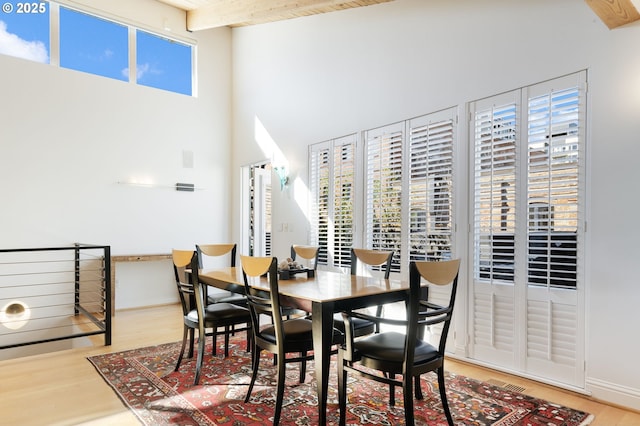 1240 NW Hoyt St Unit 6, Portland, OR 97209 - dining room featuring baseboards, a high ceiling, beam ceiling, and wood finished floors