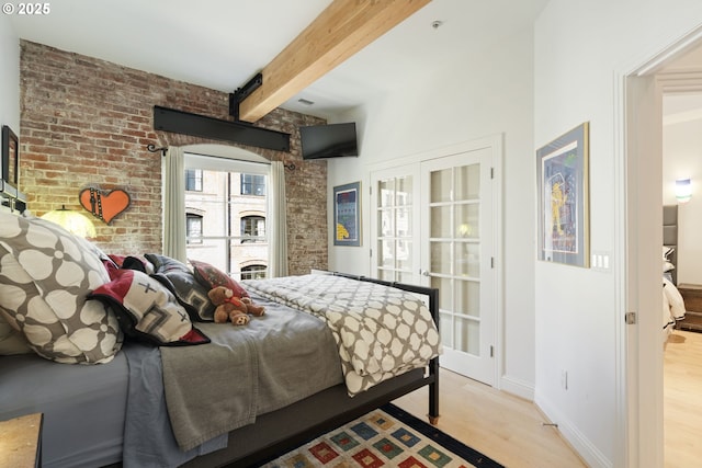 1240 NW Hoyt St Unit 6, Portland, OR 97209 - bedroom featuring baseboards, beamed ceiling, light wood finished floors, and brick wall