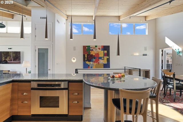 1240 NW Hoyt St Unit 6, Portland, OR 97209 - kitchen with a towering ceiling, stainless steel oven, brown cabinets, and beamed ceiling