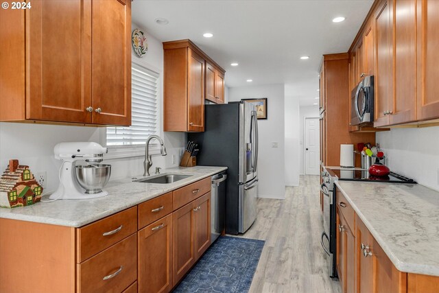 kitchen with light stone countertops, stainless steel appliances, light hardwood / wood-style floors, and sink