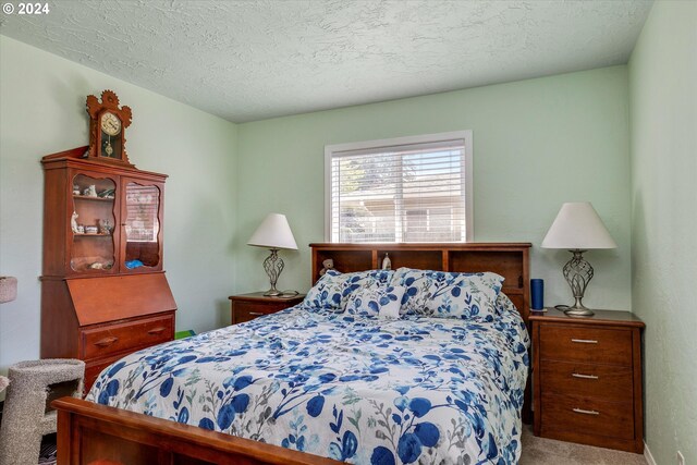 bedroom with a textured ceiling and light colored carpet