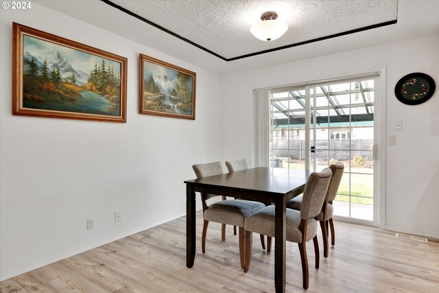 dining area featuring light hardwood / wood-style floors and a textured ceiling