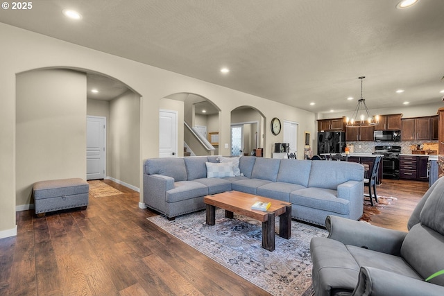 802 NW Green Forest Cir, Redmond, OR 97756 - living room with arched walkways, recessed lighting, dark wood-style flooring, a chandelier, and stairway