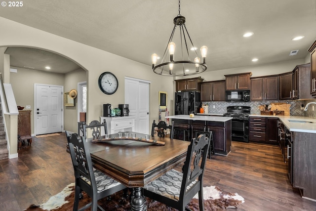 802 NW Green Forest Cir, Redmond, OR 97756 - dining room with arched walkways, dark wood finished floors, a chandelier, and recessed lighting