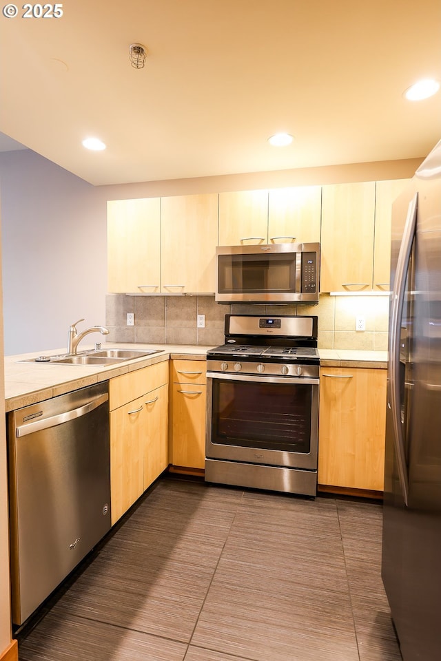 kitchen featuring decorative backsplash, appliances with stainless steel finishes, light countertops, light brown cabinets, and a sink