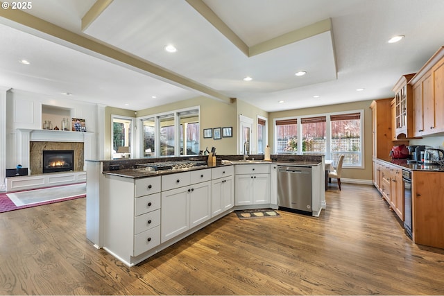 kitchen with sink, dark stone countertops, stainless steel appliances, light hardwood / wood-style floors, and white cabinets