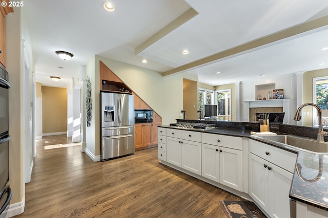 kitchen featuring appliances with stainless steel finishes, dark hardwood / wood-style floors, sink, dark stone countertops, and white cabinets