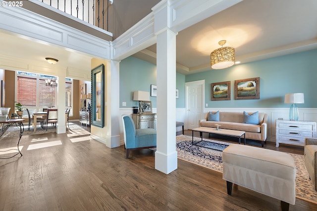 living room with an inviting chandelier, dark wood-type flooring, decorative columns, and a high ceiling