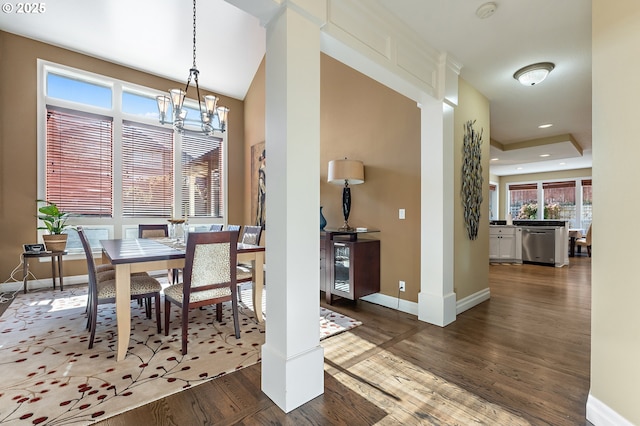 dining space with a notable chandelier, dark wood-type flooring, and ornate columns