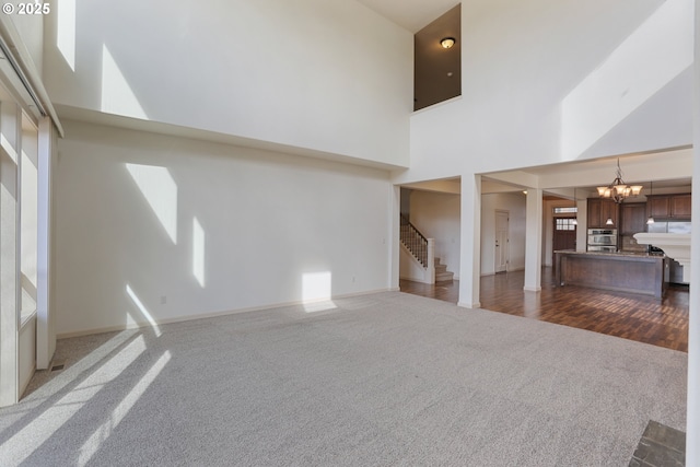 1455 NE Cooper Ln, Estacada, OR 97023 - unfurnished living room with stairs, dark wood-type flooring, a chandelier, a high ceiling, and dark carpet