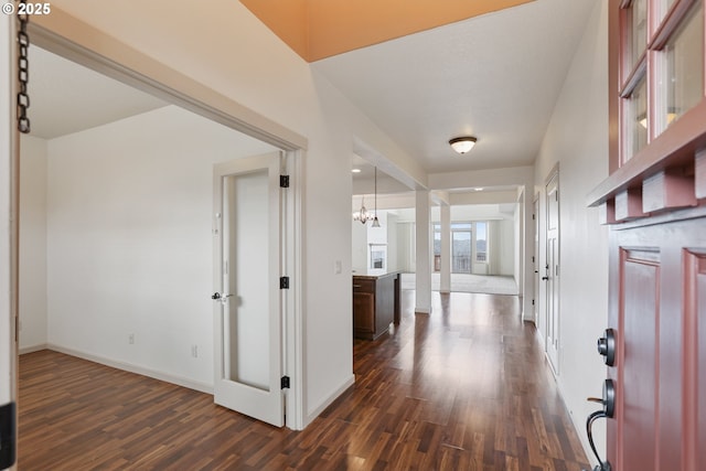 foyer entrance with an inviting chandelier, baseboards, and dark wood-type flooring