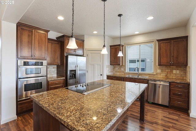 1455 NE Cooper Ln, Estacada, OR 97023 - kitchen with dark wood-style flooring, a kitchen island, a sink, pendant lighting, and appliances with stainless steel finishes